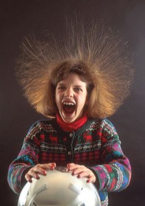 Girl with hair standing on end because of static electricity while touching a vandergraf generator. science, electricity, static, vandergraf generator, hair, girl, surprise, excitement, fear, fun